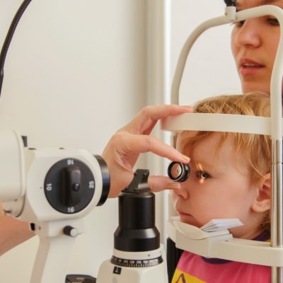 Child's ophthalmology - doctor optometrist checks eyesight for patient - little girl